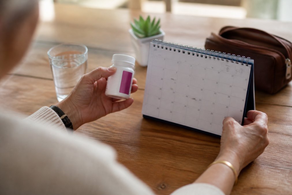 Close-up of a person's hands holding a calendar and medication bottle, suggesting tracking hormone therapy progress over time