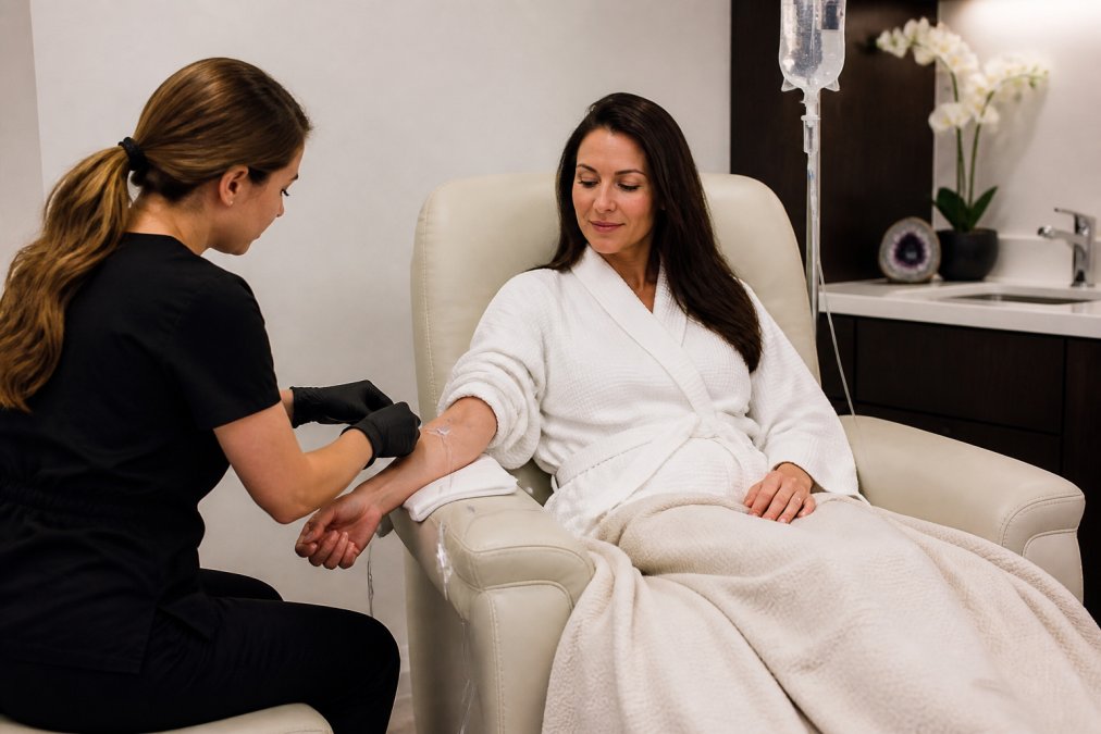 Medical professional administering NAD+ intravenous infusion to patient in modern wellness clinic with soft lighting and sterile equipment visible